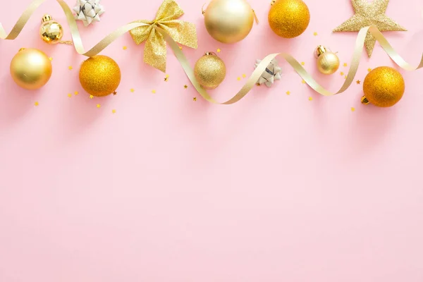 Яскраві блискучі золоті валізи, стрічки. стильні різдвяні прикраси зверху борця на пастельно-рожевому тлі. Різдвяна мінімальна композиція плоского стилю. Плоский прошарок, вид зверху . — стокове фото
