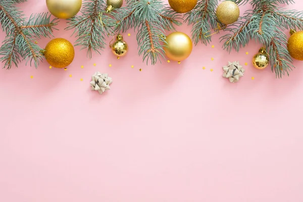 Bordure de cadre de Noël en branches de sapin, boules dorées, confettis sur fond rose pastel. Pose plate, vue du dessus, espace de copie. Noël, hiver, Nouvel An concept . — Photo