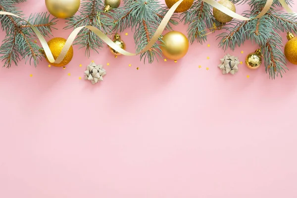 Cadre de frontière de Noël. Boules scintillantes lumineuses, branches de sapin, ruban doré sur fond rose pastel. Glamour mode composition de Noël — Photo