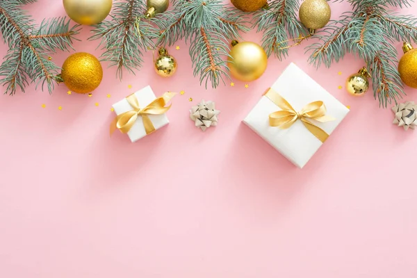 Köknar ağacı dalları ile Noel çerçeve sınırı, Noel altın topları, pastel pembe arka plan üzerinde sunar. Düz döşeme, üst görünüm.