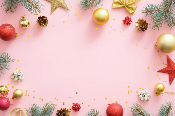 Jul ram gjord av ljusa glittrande grannlåt, granträd grenar, kottar, dekorationer på rosa pastell bakgrund. Julfest inbjudningskort mockup, vykort mall. Flat Lay. — Stockfoto