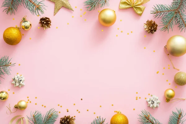 Jul ram gjord av ljusa glittrande gyllene grannlåt, granträd grenar, kottar, dekorationer på rosa pastell bakgrund. Julfest inbjudningskort mockup, vykort mall. Flat Lay. — Stockfoto