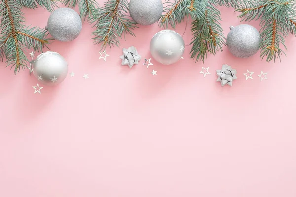Noel tatili kompozisyonu. Noel ağacı köknar dalları, kopya alanı ile pembe pastel arka plan üst sınırında gümüş topları. Düz lay, üst görünümü, Xmas glamour afiş mockup, davetiye kartı.