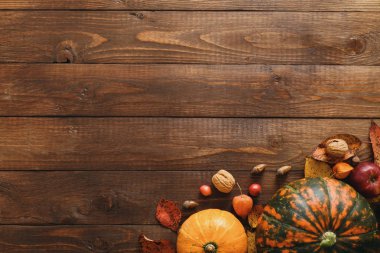 Sonbahar kompozisyonu. Kabaklar, düşmüş yapraklar, meşe palamudu, kırmızı meyveler, tahta masada ceviz. Mutlu Şükran günü konsepti. Düz döşeme, üst görünüm, kopyalama alanı