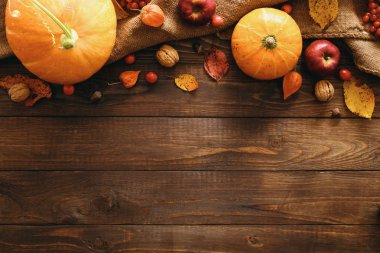 Kabak, battaniye, kurutulmuş sonbahar yaprakları, elma, kırmızı çilek, ahşap masa üzerinde ceviz yapılmış Sonbahar çerçeve sınır. Şükran Günü, Cadılar Bayramı, Sonbahar Hasadı konsepti. Düz döşeme kompozisyonu, üst görünüm