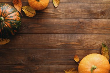 Kabaklar, kurutulmuş sonbahar yaprakları, elma, kırmızı çilek, ahşap masa üzerinde ceviz yapılmış sonbahar çerçeve. Şükran Günü, Cadılar Bayramı, Sonbahar Hasadı konsepti. Düz döşeme kompozisyonu, üst görünüm, kopyalama alanı