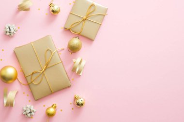 Noel kompozisyonu. Noel altın süslemeleri, hediye kutuları, baubles, kopya alanı ile pastel pembe arka plan konfeti. Düz yatıyordu, üstten bak. Tebrik kartı maketini. Noel kutlama konsepti.