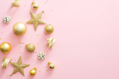Kopya alanı ile pastel pembe arka plan Noel altın süslemeleri. Parıltılı süsler, yıldızlar, konfetiler. Düz yatıyordu, üstten bak. Noel, kış tatilleri, Yeni Yıl konsepti
