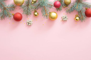 Noel çerçevesi parlak ışıltılı süsler, köknar ağacı dalları, pembe pastel arka plan süslemeleri yapılmış. Noel partisi davetiye kartı mockup, kartpostal şablonu. Düz döşeme, üst görünüm, genel merkez