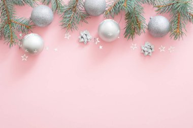 Noel tatili kompozisyonu. Noel ağacı köknar dalları, kopya alanı ile pembe pastel arka plan üst sınırında gümüş topları. Düz lay, üst görünümü, Xmas glamour afiş mockup, davetiye kartı.