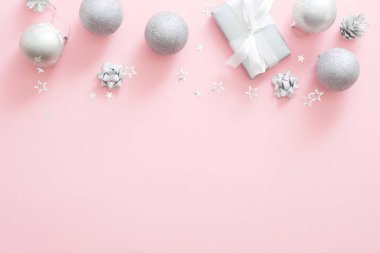 Noel süslemeleri, şık gümüş hediye kutusu, baubles, çam kozalağı, pastel pembe arka plan konfeti. Minimal düz döşeme stili kompozisyon, üst görünüm, kopyalama alanı. Noel moda glamour kavramı.