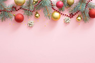 Noel tatili kompozisyonu. Noel ağacı köknar dalları, kopya alanı ile pastel pembe arka plan üst sınırında renkli topları. Banner maket, kartpostal şablonu. Düz döşeme, üst görünüm, genel merkez.