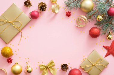 Kopya alanı ile pastel pembe arka plan üzerinde Flatlay Noel tatili kompozisyon. Üst görünüm Xmas ağaç köknar dalları, kırmızı ve altın topları, hediye kutusu, pone konileri. Noel tebrik kartı mockup.