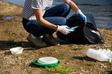 Nehrin kıyısında plastik çöp toplayan gönüllü bir kadın. Temizlik ortamı kavramı