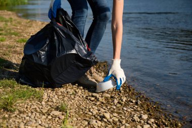 Nehrin kıyısında plastik çöp toplayan gönüllü bir kadın. Temizlik ortamı kavramı