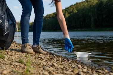 Nehirden plastik çöp toplayan gönüllü bir kadın. Temizlik ortamı kavramı