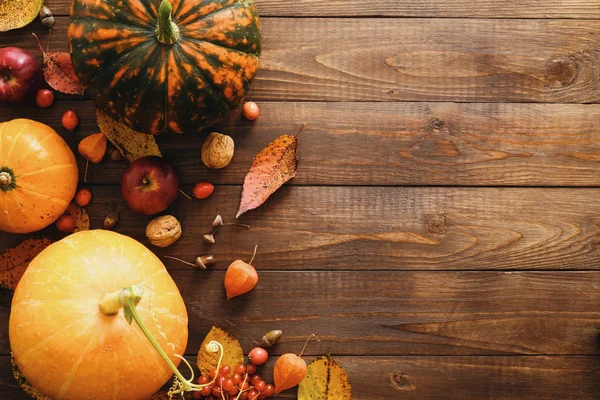 Şükran Günü konseptin kutlu olsun. Olgun turuncu balkabaklarıyla sonbahar kompozisyonu, dökülen yapraklar, kırsal ahşap masadaki kuru çiçekler. Düz konum, üst görünüm, kopyalama alanı.