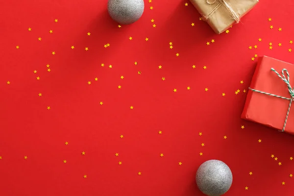 Red Christmas background with decorations. Top view present gift boxes, silver balls, golden sparkle confetti. Flat lay composition, copy space. Christmas, New Year concept. Xmas banner mockup — Stock Photo, Image