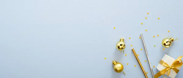 Fond de Noël avec cadeau doré ou boîte cadeau, boules, pailles à boire, décorations de vacances sur la vue de dessus de table pastel bleu. Modèle de bannière Noël ou Nouvel An avec espace de copie pour le texte . — Photo