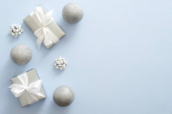 Décoration festive de Noël en argent, boules, boîte cadeau avec arc sur fond bleu pastel. Joyeux Noël et Joyeuses Fêtes carte de vœux, maquette de bannière Web, modèle de carte postale . — Photo