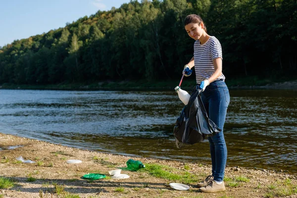 Sahilde plastik çöp toplayan gönüllü bir kadın. Temizlik ortamı kavramı