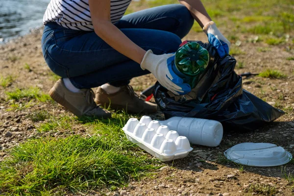 Eine freiwillige Frau sammelt Plastikmüll am Ufer des Flusses. Umweltkonzept zur Reinigung — Stockfoto
