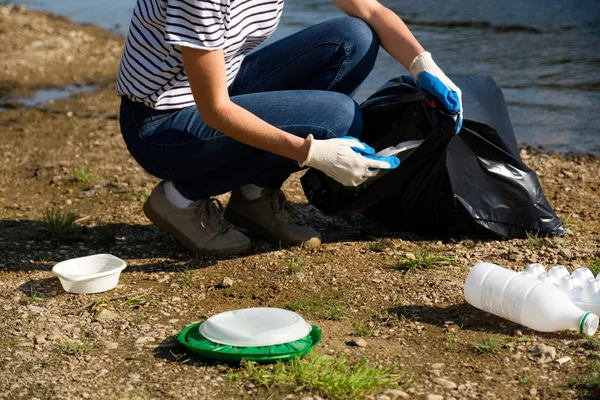 Eine freiwillige Frau sammelt Plastikmüll am Ufer des Flusses. Umweltkonzept zur Reinigung — Stockfoto