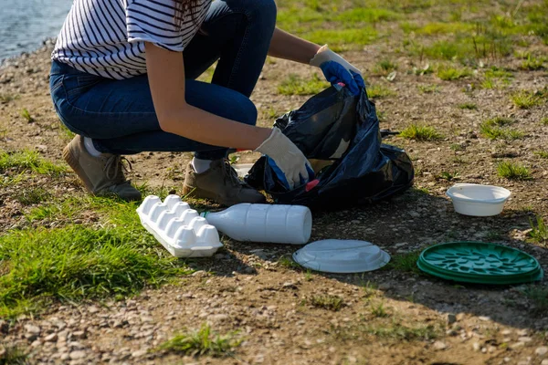 Eine freiwillige Frau sammelt Plastikmüll am Ufer des Flusses auf. Umweltkonzept zur Reinigung — Stockfoto