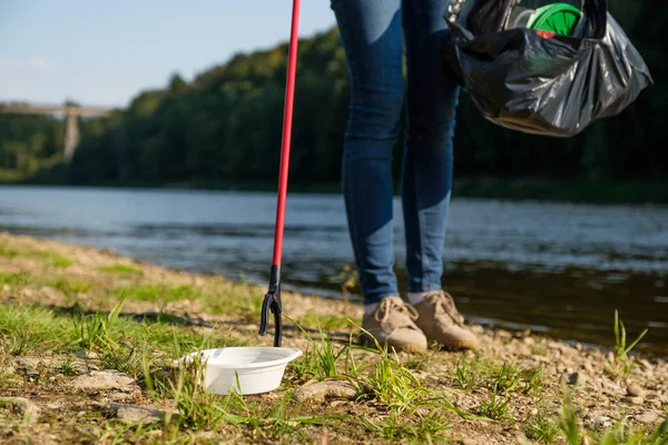 Eine freiwillige Frau sammelt Plastikmüll am Ufer des Flusses auf. Umweltkonzept zur Reinigung — Stockfoto