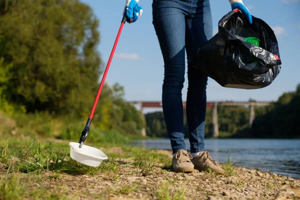 Mujer voluntaria recogiendo basura plástica en la costa del río. Concepto de ambiente de limpieza —  Fotos de Stock