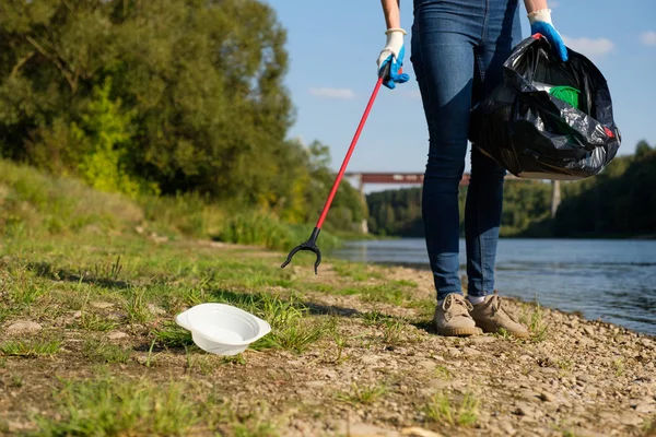 Εθελόντρια γυναίκα που μαζεύει πλαστικά σκουπίδια στην ακτή του ποταμού. Έννοια περιβάλλοντος καθαρισμού — Φωτογραφία Αρχείου