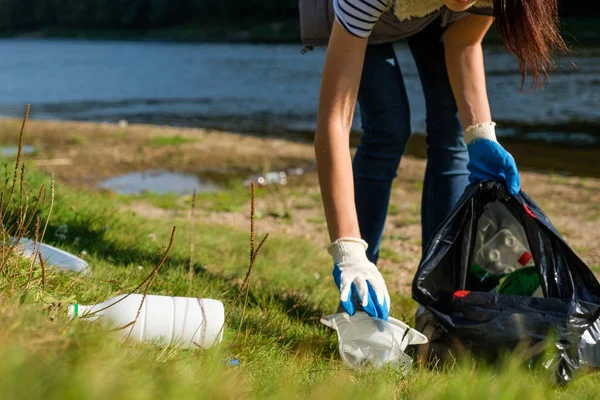 Donna volontaria che raccoglie rifiuti di plastica sulla costa del fiume. Concetto ambiente di pulizia — Foto Stock