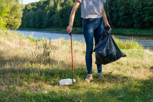 Mujer voluntaria recogiendo basura plástica en la costa del río. Concepto de ambiente de limpieza — Foto de Stock