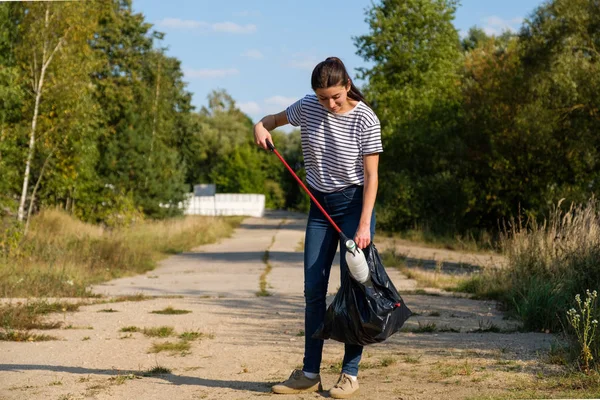 Donna volontaria che raccoglie rifiuti di plastica nella foresta. Concetto ambiente di pulizia — Foto Stock