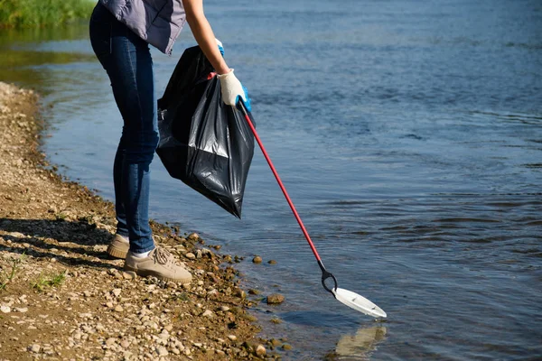 Εθελόντρια γυναίκα που μαζεύει πλαστικά σκουπίδια στην ακτή του ποταμού. Έννοια περιβάλλοντος καθαρισμού — Φωτογραφία Αρχείου