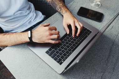 Üst görünüm erkek elleri klavyede yazarken kafede dizüstü bilgisayar kullanarak açık havada, taşınabilir bilgisayarda çalışan işadamı serbest, wifi kullanarak internette gezinmek, e-posta kontrol, program kodu yazmak