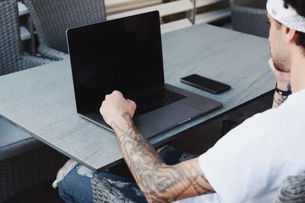 Tatuerade unga frilansare arbetar med nya Startup projekt i Coffee Shop, med hjälp av laptop och och trådlös anslutning till 4G Internet, bakifrån. — Stockfoto