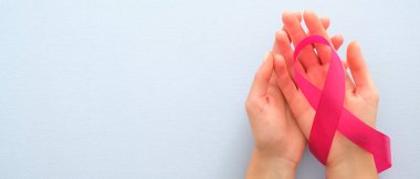 Kopya alanı ile meme kanseri farkındalık ay yatay afiş. Mavi arka plan üzerinde pembe kurdele tutan kadın elleri. Sağlık ve tıp konsepti.