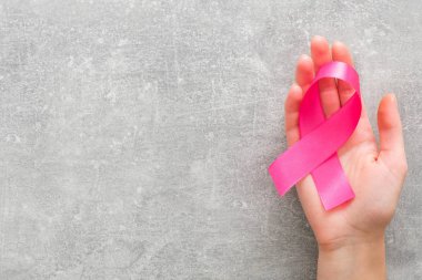 Pembe kanser farkındalık kurdelesi tutan kadın eli. Sağlık, hayır, insan ve tıp kavramı.
