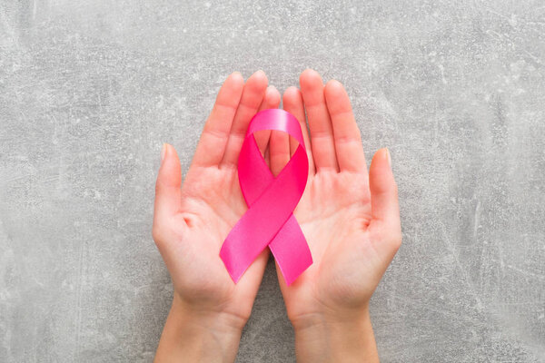 Woman���s hands holding pink breast cancer awareness ribbon. Healthcare and medicine concept. Breast cancer awareness month card.