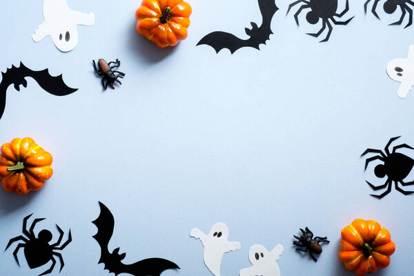 Happy halloween holiday concept. Halloween decorations, spiders, bats, ghosts, pumpkins on blue background. Flat lay, top view, overhead.