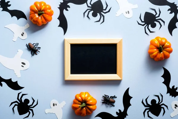 Buon concetto di festa di Halloween. Decorazioni di Halloween, cornice, ragni, pipistrelli, fantasmi, zucche su sfondo blu. Posa piatta, vista dall'alto, sopraelevato . — Foto Stock