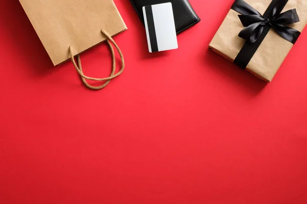 Fekete pénteki vásár. Keret készült ajándék doboz, betéti kártya és bevásárló táska piros háttér — Stock Fotó