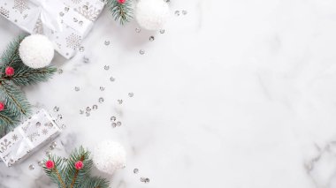 Noel veya yeni yıl çerçevesi köknar ağacı dalından, beyaz toplardan, hediye kutularından ve mermer zemin üzerinde konfetiden yapılmıştır. Noel boyu afiş modeli. Düz yatıyordu, üstten, yukarıdan.