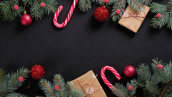Christmas banner. Black Xmas background with candy cane, decorations, fir tree branches and gift boxes wrapped craft paper. Christmas frame, greeting card template, web banner mockup. Flat lay, top vi — 스톡 사진