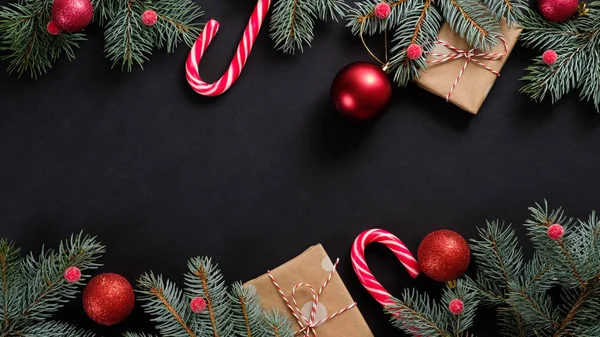 クリスマスツリーモミの枝、装飾、キャンディー杖、黒い背景のギフトボックス。フラットレイアウト、トップビュー、オーバーヘッド。クリスマスのバナーモックアップ. — ストック写真