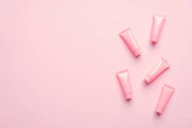 Pembe arka planda boş kozmetik tüpleri. Güzellik ürünü ambalaj tasarımı, minimal stil. Düz yatış, üst görünüm.