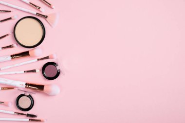 Farklı makyaj fırçaları, makyaj malzemeleri, pembe arka planda toz ve göz farı. Düz yerde, üst tarafta. Makyaj mağazası afiş tasarımı.