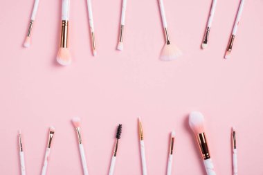 Pembe arka planda makyaj fırçası çerçevesi. Güzellik salonu afişi. Düz yatış, üst görünüm.