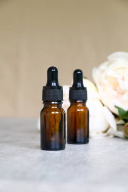 Kehribar boş cam damlası şişesi, serum ya da gerekli yağ ve şakayık çiçekleri. Doğal organik kozmetik konsepti.